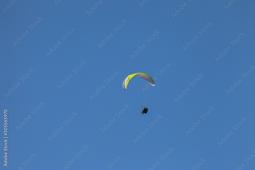 a man paragliding solo on the blue sky over the Dolomites in Italy in a sunny day a man paragliding solo on the blue sky over the Dolomites in Italy in a sunny day