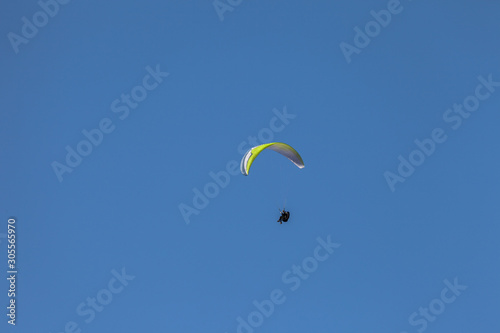 a man paragliding solo on the blue sky over the Dolomites in Italy in a sunny day