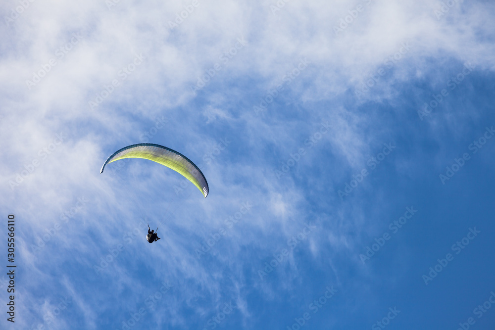 a man paragliding solo on the blue sky over the Dolomites in Italy in a sunny day a man paragliding solo on the blue sky over the Dolomites in Italy in a sunny day