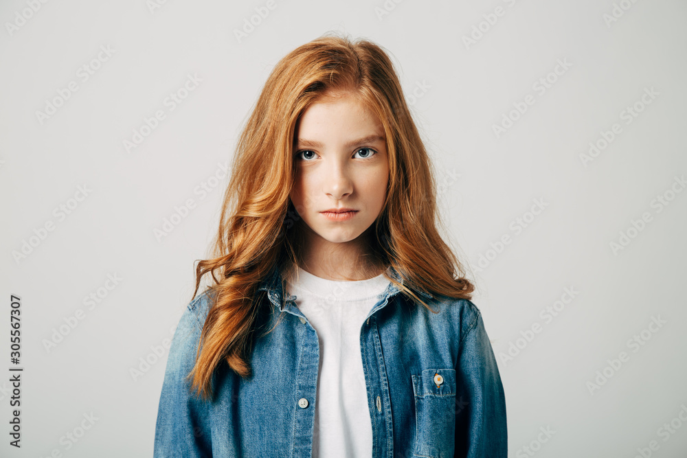 The red-haired teen girl is very offended by her parents. She is angry and look at the camera. Isolated The red-haired teen girl is very offended by her parents. She is angry and look at the camera. Isolated
