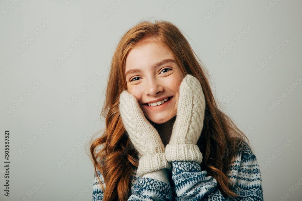The girl in a sweater smiles, warming her face with gloves on her hands. Warm knitted gloves were very warm and comfortable The girl in a sweater smiles, warming her face with gloves on her hands. Warm knitted gloves were very warm and comfortable