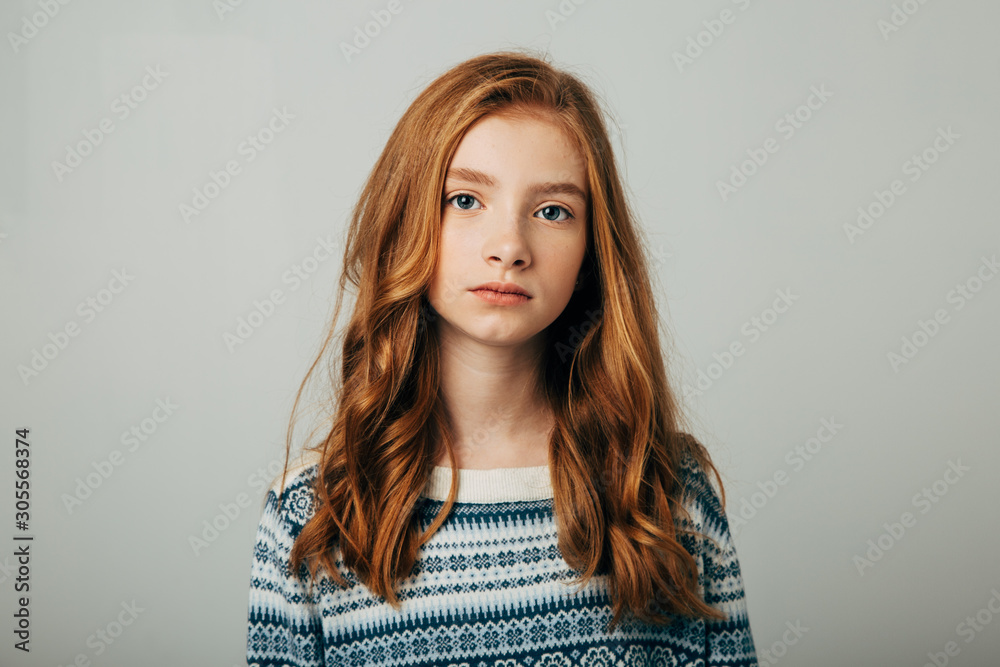 A young red-haired girl in a blue sweater looks at the camera. A girl with a worried video is trying to draw your attention to the problems of society. Isolate on a white background. A young red-haired girl in a blue sweater looks at the camera. A girl with a worried video is trying to draw your attention to the problems of society. Isolate on a white background.