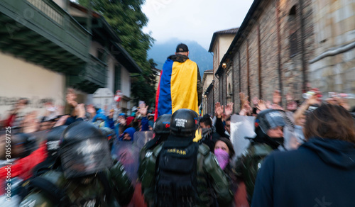 A man with a colombian flag in her body in front of a lot people