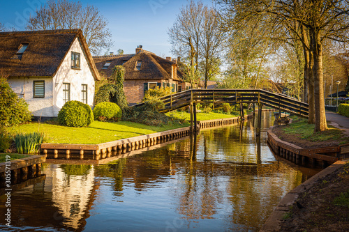 Lovely landscape along canal with footbridges and beautiful thatched cottages, Giethoorn, Netherlands
