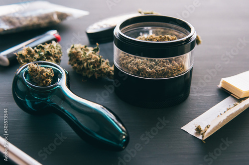 Cannabis legalisation. Marijuana smoking pipe CBD and THC on buds in cannabis. Macro Cannabis buds weed on black wood background.