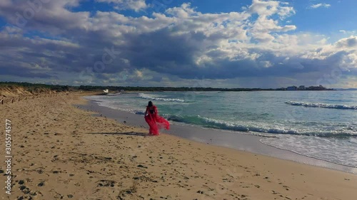 a girl in a red dress runs and dances on the beach es Trenc Majorca Spain