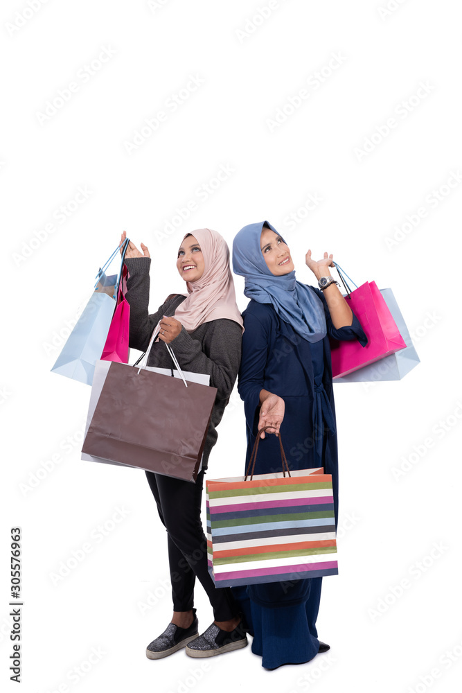 Asian young and old veiled women carrying some shopping bags at isolated background