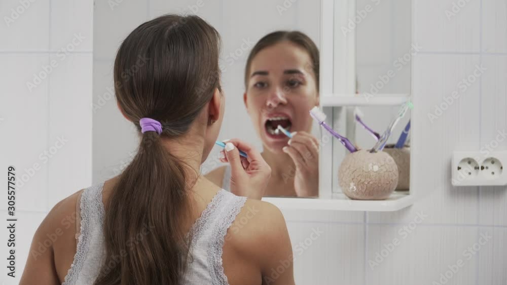 Oral hygiene with metal braces. Brushes teeth with a special toothbrush and toothpaste in the bathroom opposite the mirror. The average plan Oral hygiene with metal braces. Brushes teeth with a special toothbrush and toothpaste in the bathroom opposite the mirror. The average plan