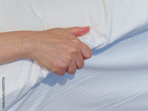 Close up image of Asian woman hand grasp white bed sheet.