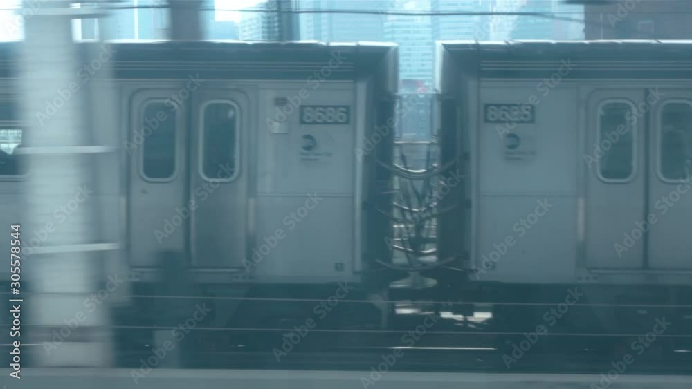 Looking out the window of a New York City subway train in motion (Manhattan to Brooklyn) seeing another train at same speed going over the Manhattan Bridge with the skyline in the background. POV shot