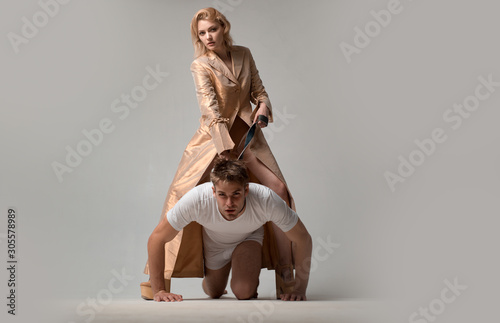 Lovers man and woman are preparing for role playing games. Dominatrix blonde woman holding her husband in collar and make him obey. New sensual date idea concept.