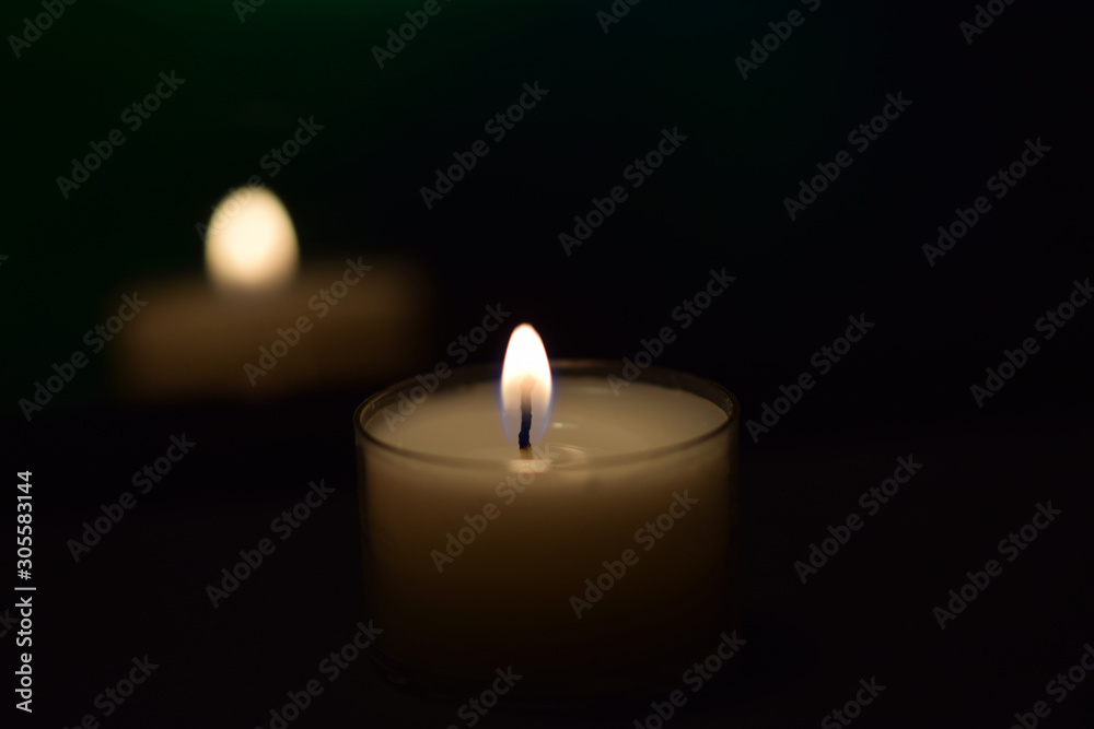 Kerze leuchtet im Dunkeln - kleine weiße Kerze auf schwarzem Hintergrund Kerze leuchtet im Dunkeln - kleine weiße Kerze auf schwarzem Hintergrund