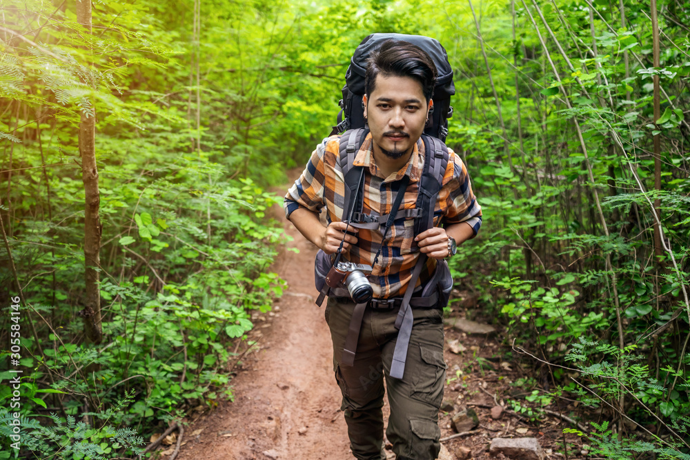 man traveler with backpack walking and looking in the forest