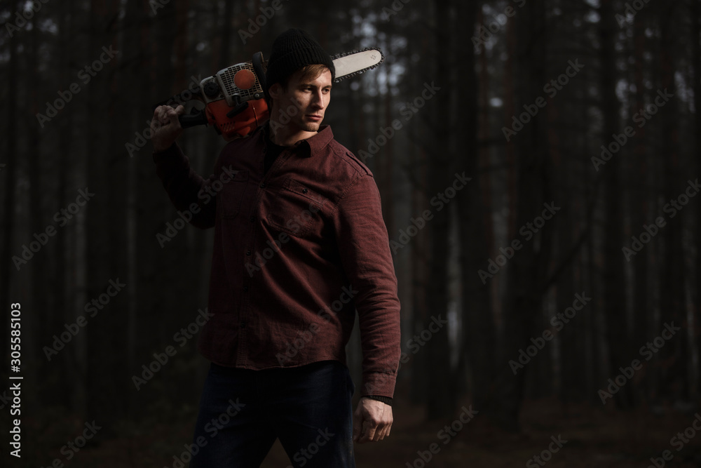 Lumberman working with chainsaw in the forest. Strong lumberjack with the chainsow in the forest.Stylish lumberman getting ready for work. Lifestyle. Lumberman working with chainsaw in the forest. Strong lumberjack with the chainsow in the forest.Stylish lumberman getting ready for work. Lifestyle.