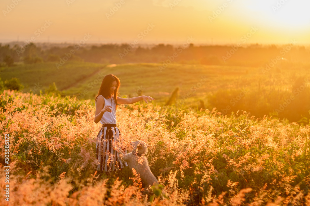 Fototapeta premium Trendy girl in stylish summer dress feeling free in the field with flowers in sunshine.