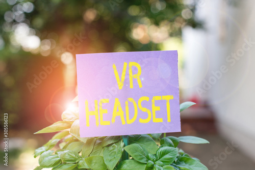 Handwriting text Vr Headset. Conceptual photo headmounted device that provides virtual reality for the wearer Plain empty paper attached to a stick and placed in the green leafy plants © Artur