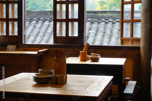 Chopsticks, cup and bowl on the wooden table, with oriental looking background,