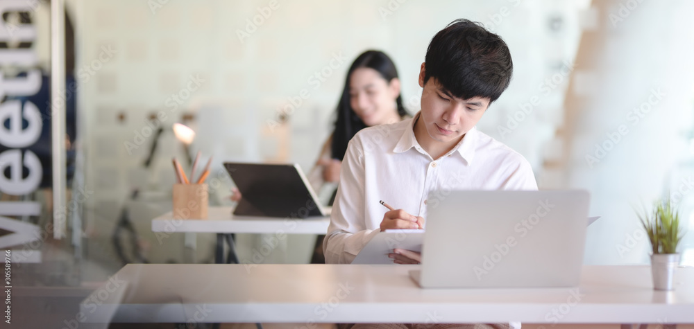 Young professional male designer working on his project while using laptop computer Young professional male designer working on his project while using laptop computer