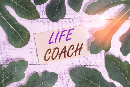 Writing note showing Life Coach. Business concept for someone who helps identify your goals and plan to achieve them Leaves surrounding notepaper above a classic wooden table photo