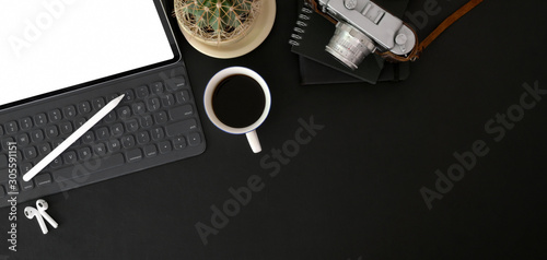 Top view of trendy photographer workplace with mock up digital tablet ,camera and office supplies on black table