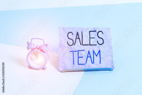 Handwriting text writing Sales Team. Conceptual photo they are responsible for of selling products or services Mini size alarm clock beside a Paper sheet placed tilted on pastel backdrop