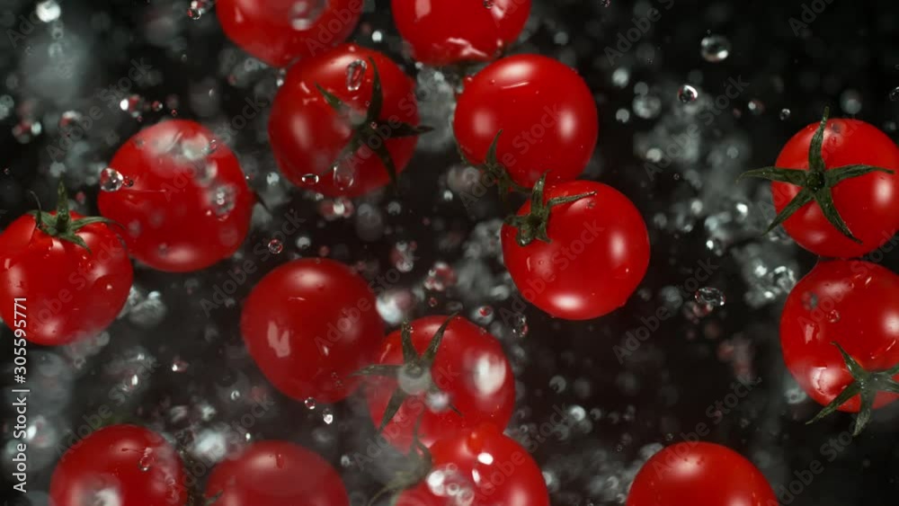 Fresh cherry tomatoes with water droplets exploding on black background. Filmed on high speed cinema camera, 1000fps. Fresh cherry tomatoes with water droplets exploding on black background. Filmed on high speed cinema camera, 1000fps.