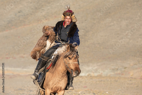 Kazakh eagle hunters partaking in a traditional wrestling match. Two wrestlers on horseback start pulling on a sheep skin, the one who retrieves it, is the winner. Ulgii, Mongolia.