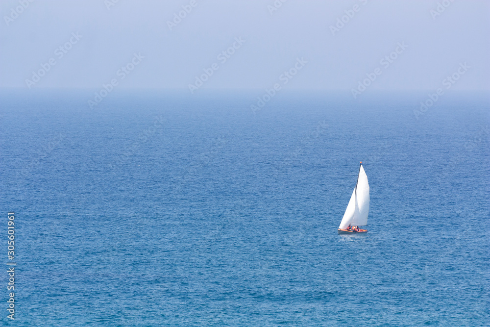 Seascape with white sailing boat and the haze on the horizon