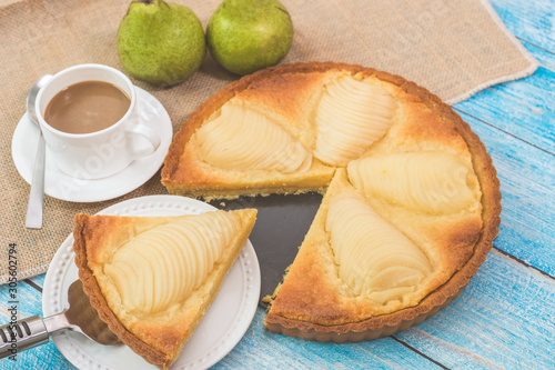 Delicious home bake poached pear tart pie, as known as Tarte Bourdaloue, a cup of coffee latte. French popular recipe that gets the name from a street in Paris. Food on table concept. photo