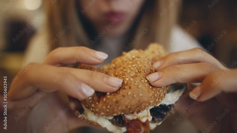 Eating burger. Junk food, modern life concet. Filmed on cinema camera. 12 bit color space.