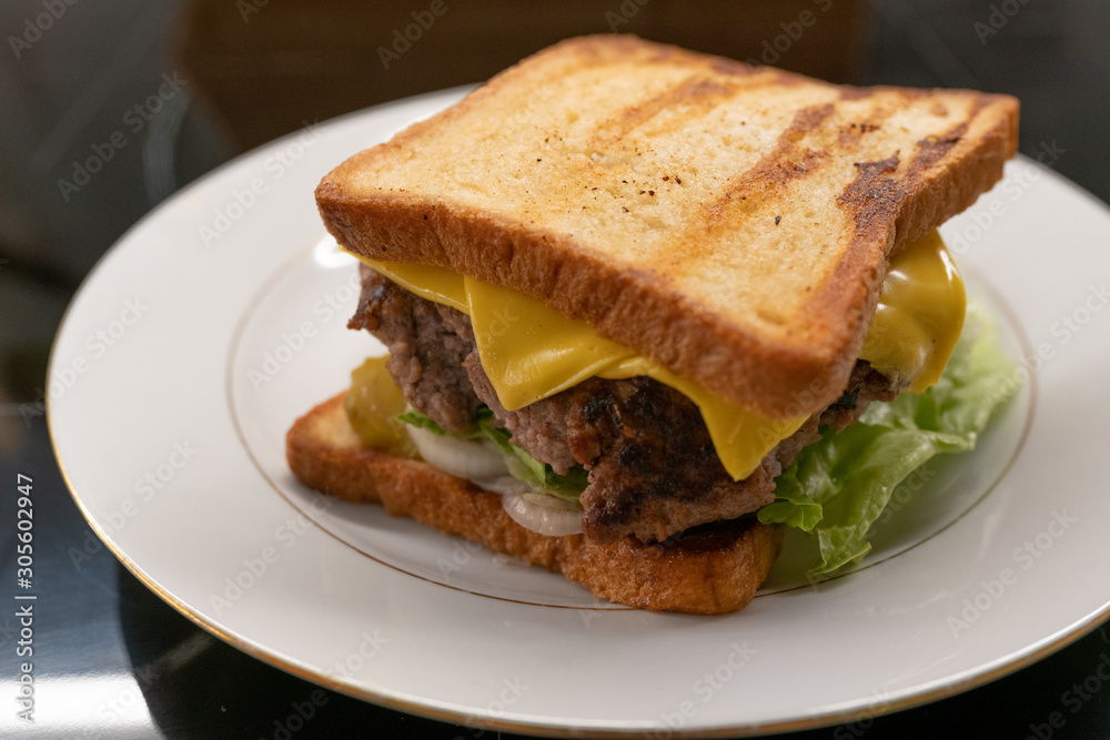 Homemade sandwich with large juicy beef Patty and salad on the plate closeup. Selective focus
