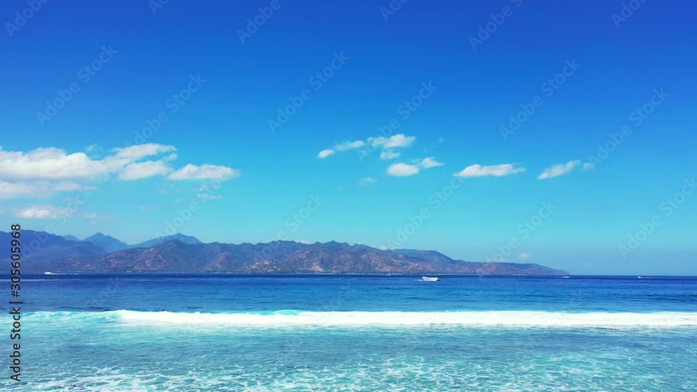 Stunning Blue Waves And Sky Making The Beautiful Scenery From The Beach Of Indonesia With Mountains In The Background - Wide Pan Shot Stunning Blue Waves And Sky Making The Beautiful Scenery From The Beach Of Indonesia With Mountains In The Background - Wide Pan Shot