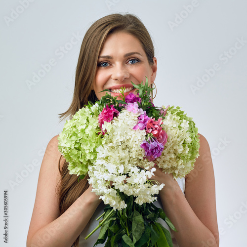 face portrait of smiling woman holding big flowers bouquet in front of face.