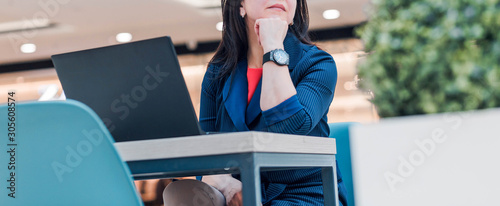 Stylish business woman working on a laptop in a bright office. Woman is in a pensive pose