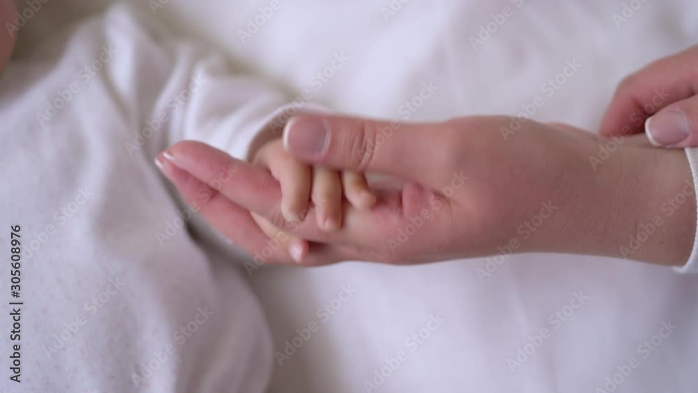Tiny infant fingers tightly holding mothers hand, mom and baby bonding, family Tiny infant fingers tightly holding mothers hand, mom and baby bonding, family