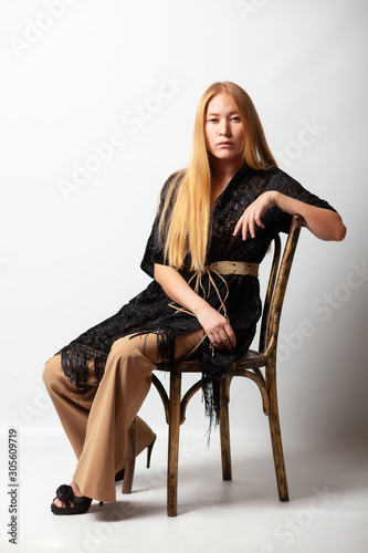 The blonde with a chair in full growth on a gray background.