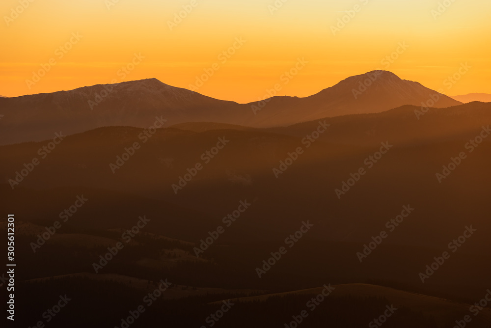Evening in Carpathians Mountains. The sun disappeared for gorizon, a sunset. Shadows are condensed, beautiful clouds. Bright orange colors. Tranquility evening