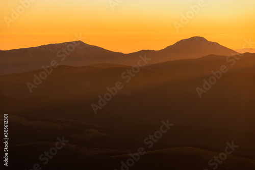 Evening in Carpathians Mountains. The sun disappeared for gorizon, a sunset. Shadows are condensed, beautiful clouds. Bright orange colors. Tranquility evening