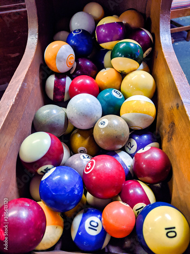 Close up  selective focus on a wooden bin filled with colorful  old billiard table balls.