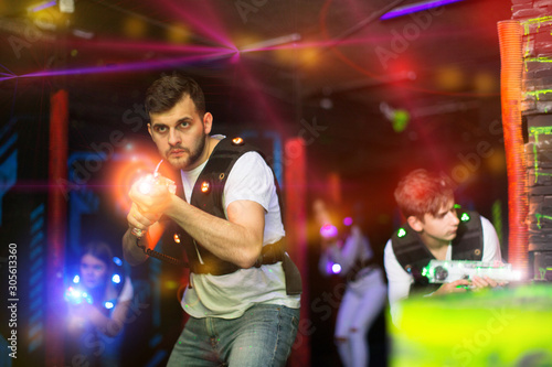Emotional guy playing laser tag in colorful beams