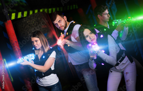 Young people in bright beams during laser tag game