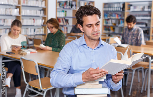 Focused man browsing books in library