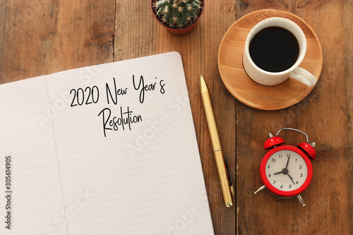 Business concept of top view 2020 year's resolution list with notebook, cup of coffee over wooden desk