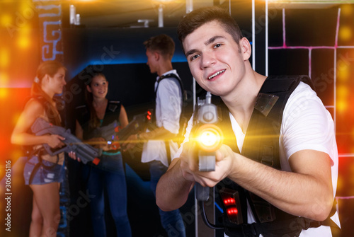 Excited  guy with laser pistol while playing lasertag with his f © JackF