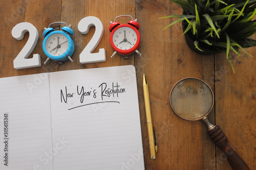 Business concept of top view 2020 year's resolution list with notebook over wooden desk