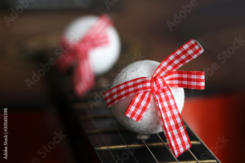 White balls with red bows on guitar photo