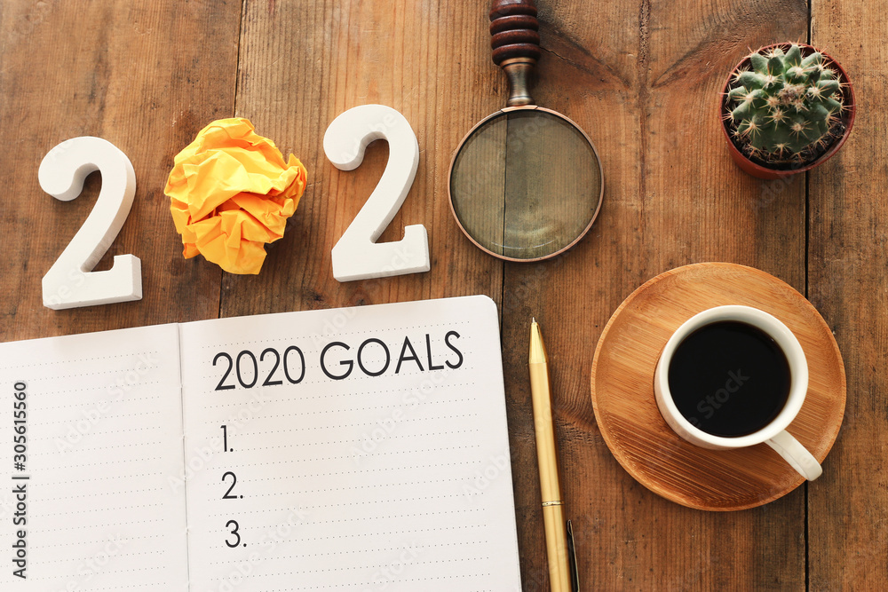 Plakat Business concept of top view 2020 goals list with notebook, cup of coffee over wooden desk