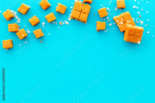 Fotografie Salted caramel pieces - paradoxical sweets - on blue background top view frame c