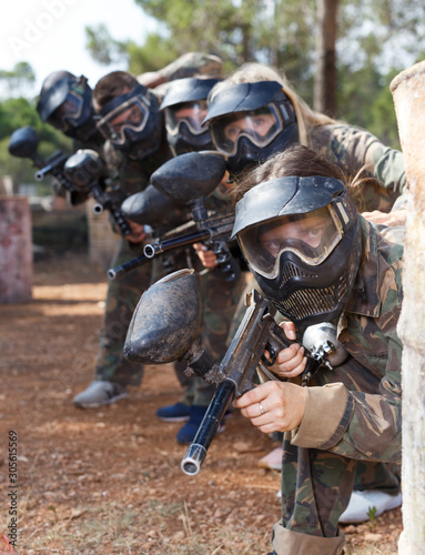 Paintball players aiming with guns