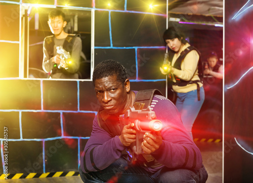 African man playing laser tag with friends